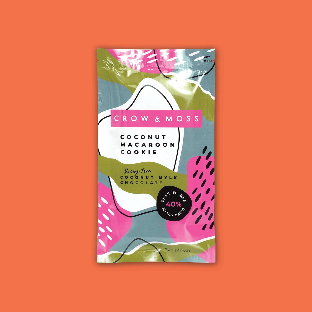 On an orangey-red background sits a package. This colorful package has different shapes in white, army green, hot pink, and light teal blue. It says "CROW & MOSS" in white, all caps block font on a hot pink background. It also says in black "COCONUT MACAROON COOKIE" in all caps block font. It says "Dairy Free COCONUT MYLK CHOCOLATE" in black script and block font. 'BEAN TO BAR SMALL BATCH 40%'. 70G (2.4OZ)