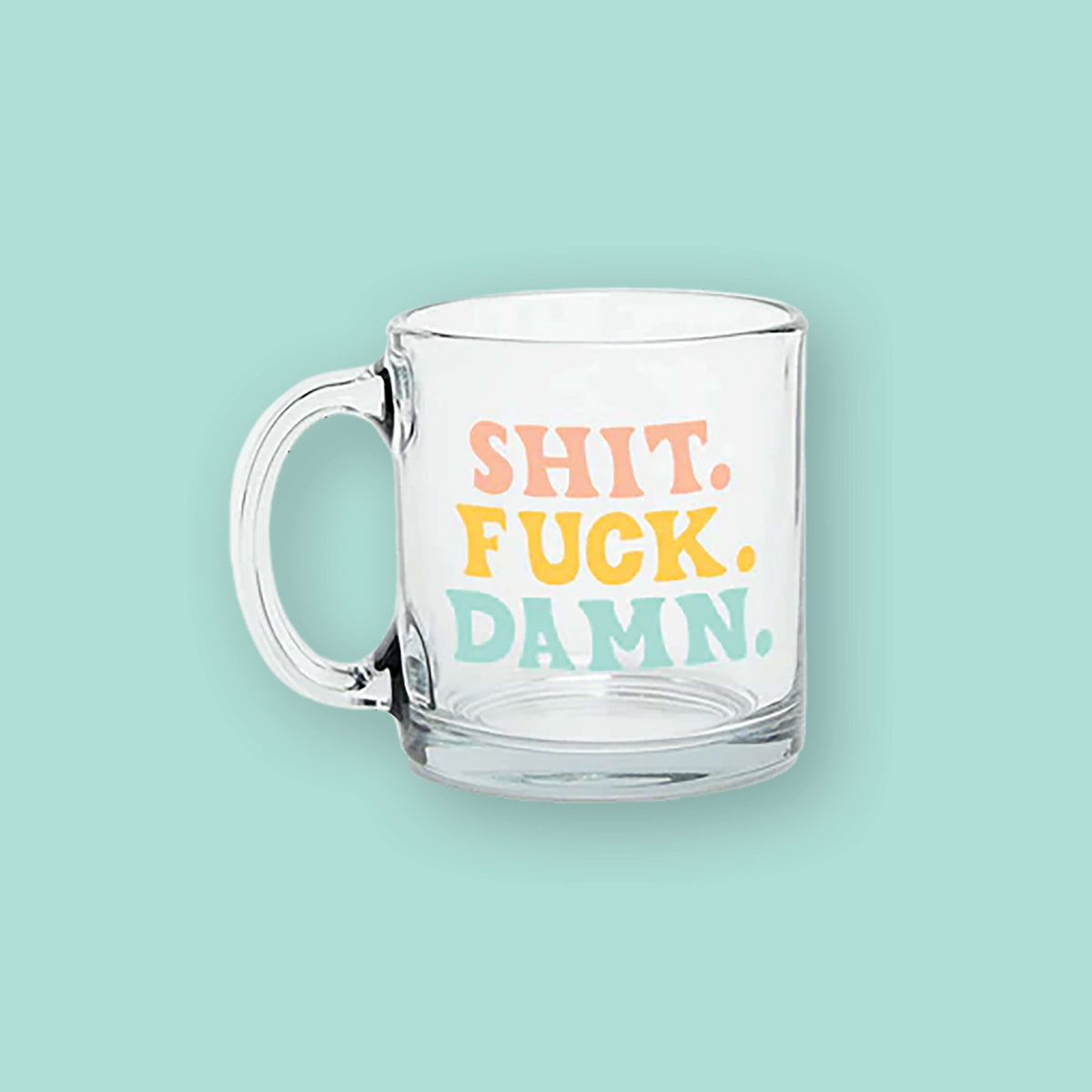 On a mint green background sits a clear mug. It says "SHIT." in peach, all caps handwritten lettering, "FUCK." in sunny mustard, all caps handwritten lettering, and "DAMN." in mint, all caps handwritten lettering. 