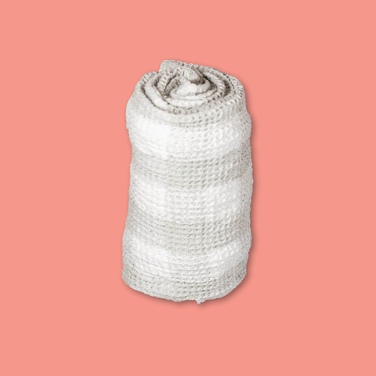 On a coral background sits a striped rolled up tea towel.