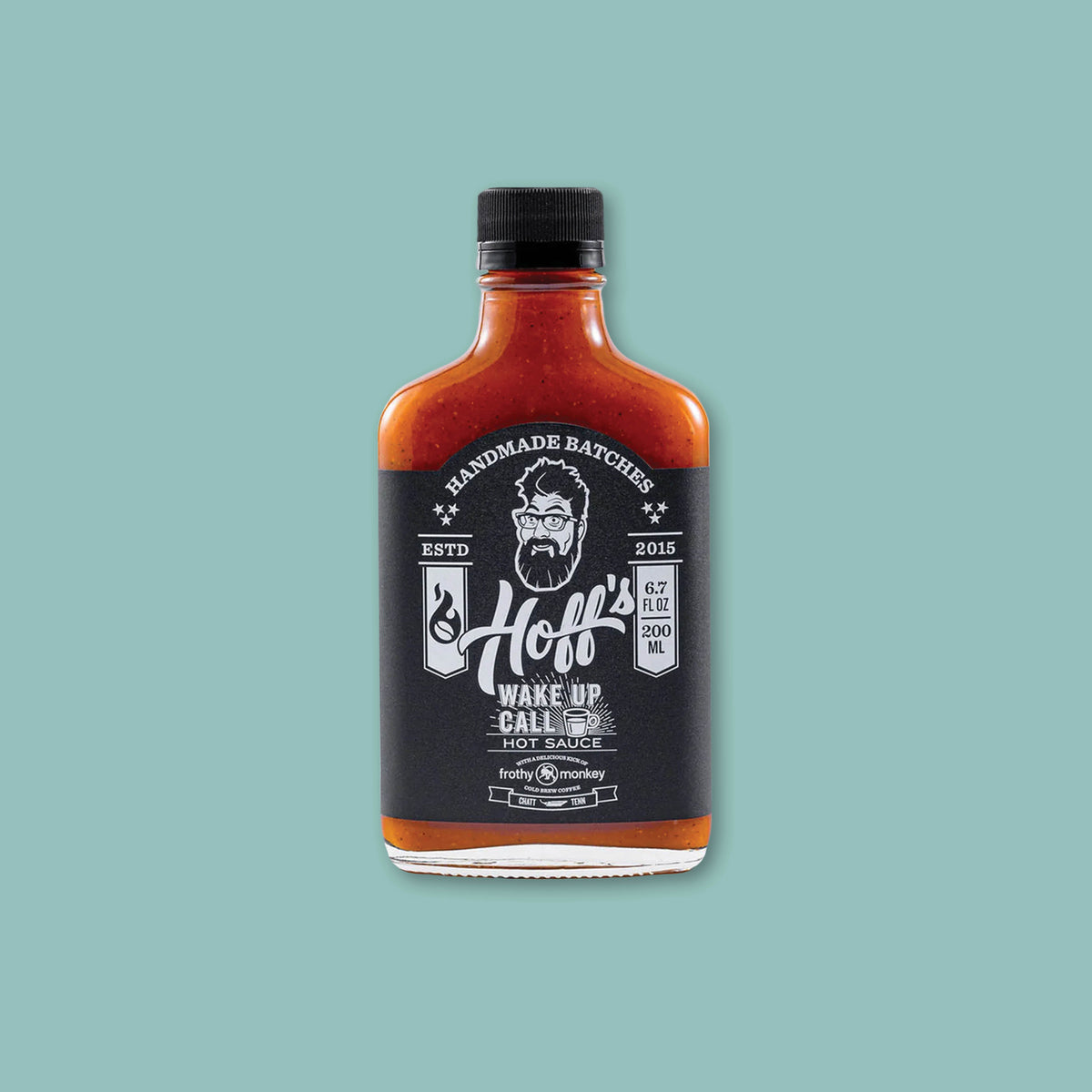 On a teal background sits a bottle of Hoff's Wake Up Call Hot Sauce with a black and white label.